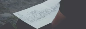 Osoba mająca projekt budowy na kolanach